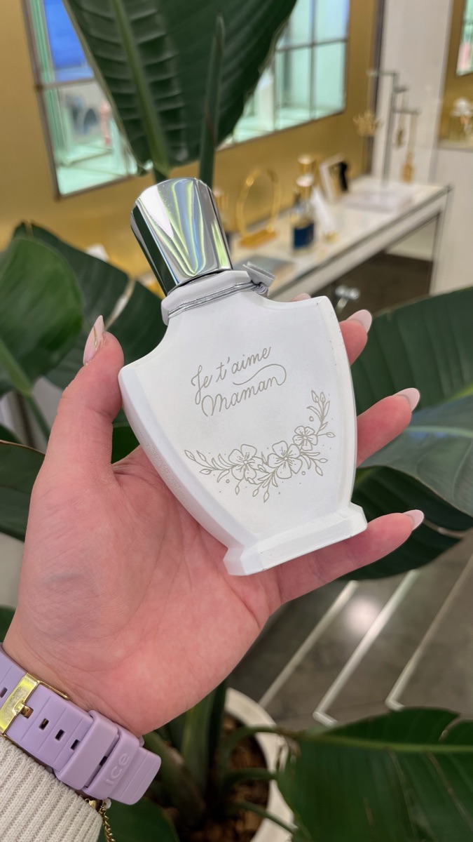 Flacon de parfum blanc gravé à la main « Je t'aime Maman » surmontant une guirlande de fleurs gravée