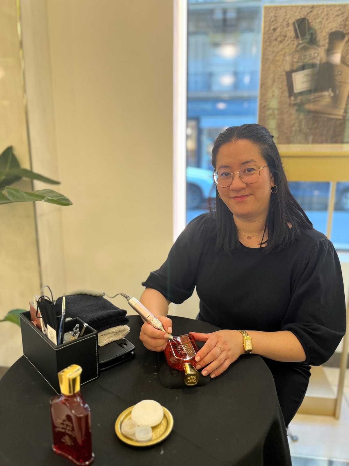 Cathy grave un flacon de parfum à la main, en boutique Creed