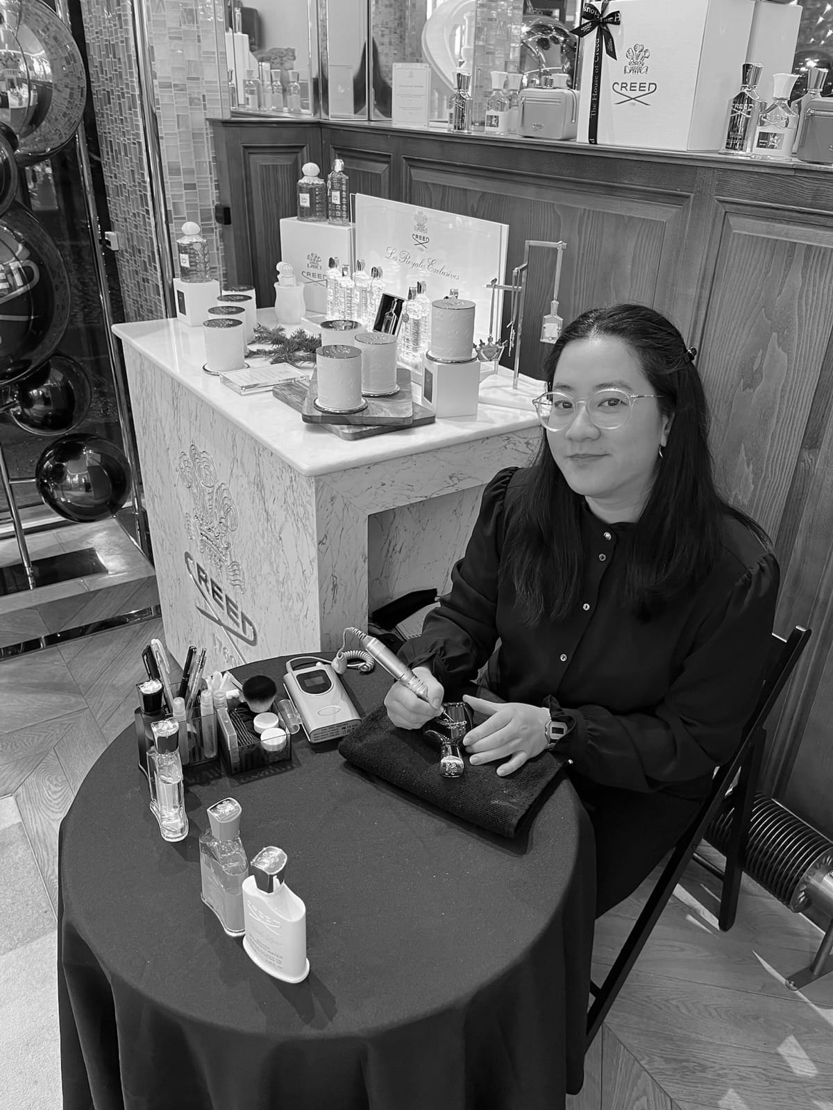 Cathy grave un flacon de parfum Creed à la main, en boutique à Paris