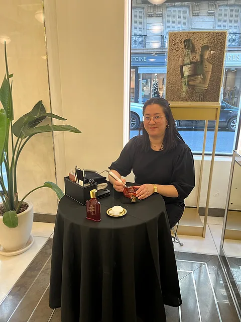 Cathy à sa table de gravure près de la vitrine d’une boutique Creed